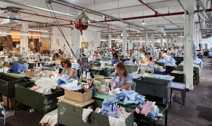 Employees sitting at sewing machines in a clothing factory